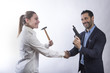 Una donna manager con un martello stringe la mano a un altro manager con una pistola  in giacca - sfondo chiaro