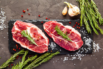 Fresh raw beef with rosemary on black background