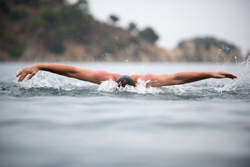 young sporting man swims in the sea dolphin style.