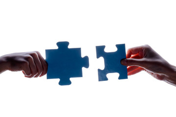 Silhouette of two hand holding couple of blue jigsaw puzzle piece on white background. concept - connection idea, sign, symbol, friendship, decision, success