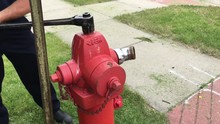 Fireman Opening Up Red Fire Hydrant With Wrench And Socket Before Dirty And Then Clear Water Finally Hit The Street.  