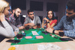 © VadimGuzhva - Young people play poker at the table.