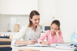 © VadimGuzhva - Mom helps my daughter do her homework in the kitchen.