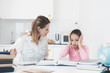 © VadimGuzhva - Mom helps my daughter do her homework in the kitchen.