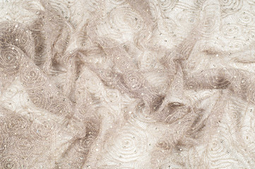 Texture, fabric, background. Lace fabric with a pattern of a circle, with a thread of gold thread