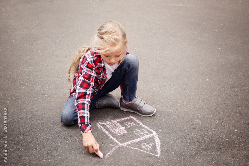 Little girl drawing house with chalk on asphalt
