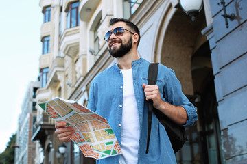 Wall Mural - Young male tourist with map on the street