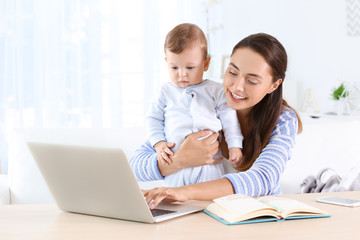 Sticker - Young mother holding baby while working in home office