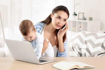 Sticker - Young mother holding baby while working in home office