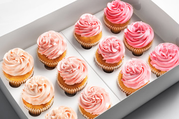 Yummy cupcakes in box on white background