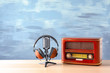 Retro radio, microphone and headphones on table against blue wall