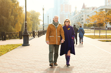 elderly couple walking in the street on autumn day