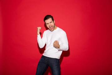 Wall Mural - Happy screaming man in sweater rejoice and looking at camera