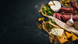 © Yaruniv-Studio - Assortment of cheeses and traditional sausages on a wooden background. Brie cheese, blue cheese, gorgonzola, fuete, salami. Free space for text. Top view.