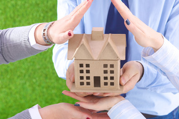 The house is in the hands of men and women on a grass background