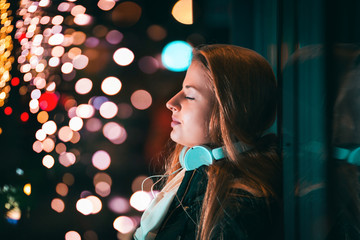 Beautiful woman at night in the city among colorful lights