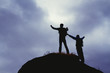© Daniel - Silhouettes of two mountain climbers on the top of a mountain with victorious gesture.