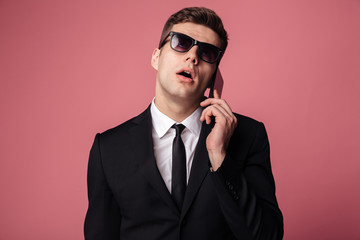 Canvas Print - Tired displeased young businessman talking by mobile phone.