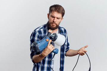 Man with a beard on a white isolated background holds construction tools for repair