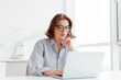 © Drobot Dean - Charming businesswoman in glasses and striped shirt working with laptop computer while siting at home