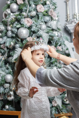 Mother putting on tiara to head of daugther during christmas celebration.