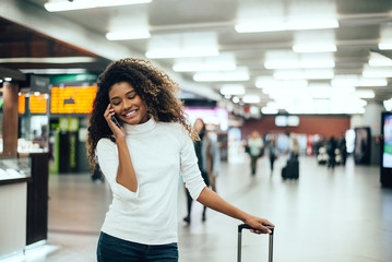 Wall Mural - Portrait of young tourist woman talking on phone at airport.