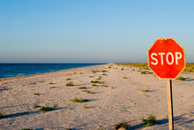 Big Red Road Prohibiting Stop Sign Standing On A Deserted Beach Yellow Sand Blue Sea Shore Clear Blue Sky Summer Warmth