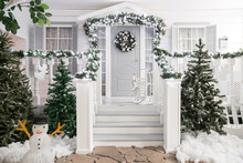 House Entrance Decorated For Holidays. Christmas Decoration. Garland Of Fir Tree Branches And Lights On The Railing