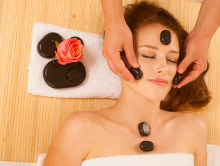 Wall Mural - attractive young beautiful woman having facial massage with mineral stone