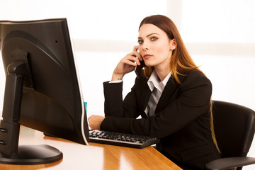 Angry business woman talks on smert phone in office at her desk