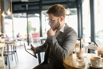 Wall Mural - Businessman using tablet in cafe