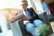 © goodluz - Businessman in airport waiting area connected with tablet