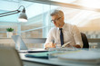 © goodluz - Businessman in office working at desk on laptop computer