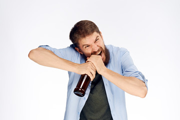 Man with a beard on a white isolated background opens a bottle of beer with his teeth, alcohol