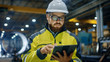 © Gorodenkoff - Industrial Engineer in Hard Hat Wearing Safety Jacket Uses Touchscreen Tablet Computer. He Works at the Heavy Industry Manufacturing Factory.