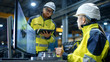 © Gorodenkoff - Inside the Heavy Industry Factory Female Industrial Engineer Works on Personal Computer She Designs 3D Engine Model, Her Male Colleague Talks with Her and Uses Tablet Computer. Low Angle Footage.