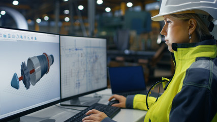 Inside the Heavy Industry Factory Female Industrial Engineer Works on the Personal Computer on the Turbine/ Engine Project in 3D Using CAD Program.