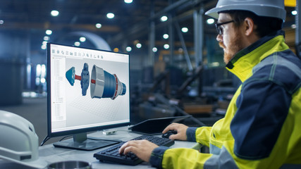 Inside the Heavy Industry Factory Industrial Engineer Works on the Personal Computer Designing Turbine/ Engine in 3D, Using CAD Program.