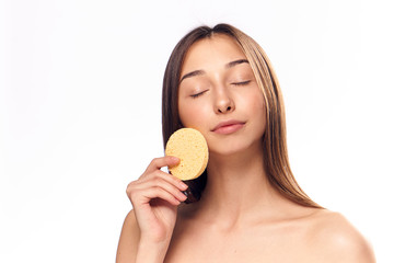 Wall Mural - Young beautiful woman on white isolated background holds a sponge for make-up removal