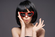 © SHOTPRIME STUDIO - Woman in black wig adjusts glasses on dark background portrait