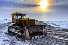 Old Industrial Dirty Yellow Tractor Under The Evening Sun In The Cloudy Winter Sky