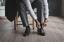 A Man In A Business Suit Ties The Laces 335.