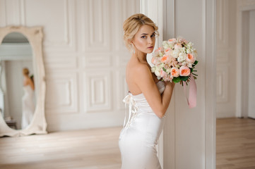 Poster - Beautiful blonde bride in the elegant white dress holding a wedding bouquet