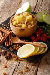 Wall Mural - Indian cuisine: apple chutney with lemon and spices close-up on the table. vertical