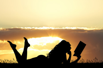 Poster - girl lying on the grass reads a book at sunset