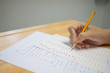Wall Mural - students hands taking exams, writing examination room with holding pencil on optical form of standar