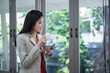 © nattanan - Smile of Beautiful Asian Businesswoman stand and holding coffee cup near the window. in office.  business successful concept.