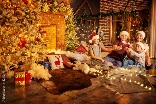 Family With Bengal Lights In The Room With A Christmas Tree And A
