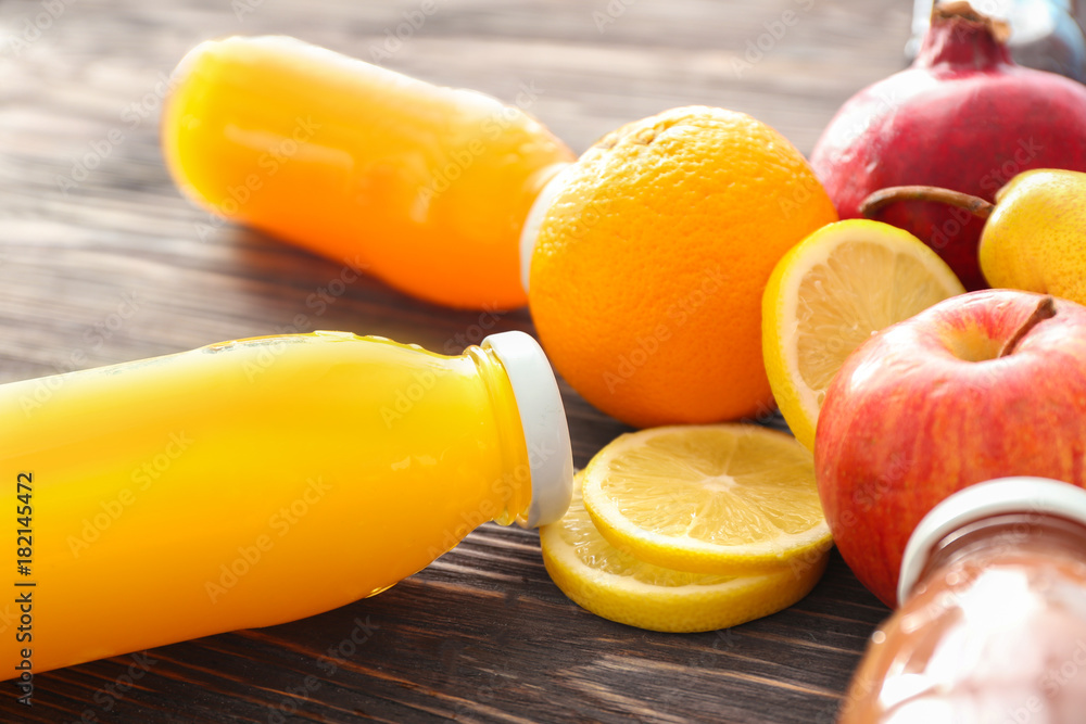 Bottles of fruit juices and ingredients on table, closeup