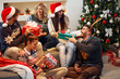 © luckybusiness - friends laughing and sharing Christmas gifts.
